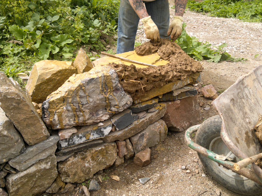 LandWorks trainee adding the first bit of cob to the sculpture