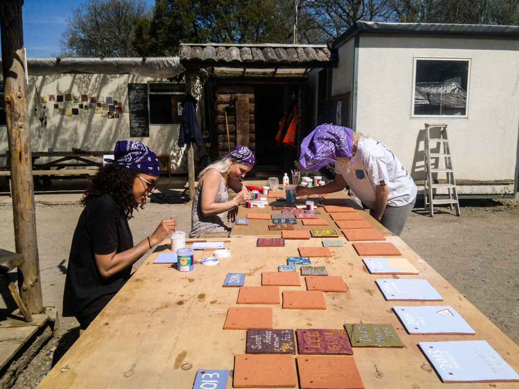 Plymouth University art students Hannah, Paige, and Megan painting ceramic clay tiles